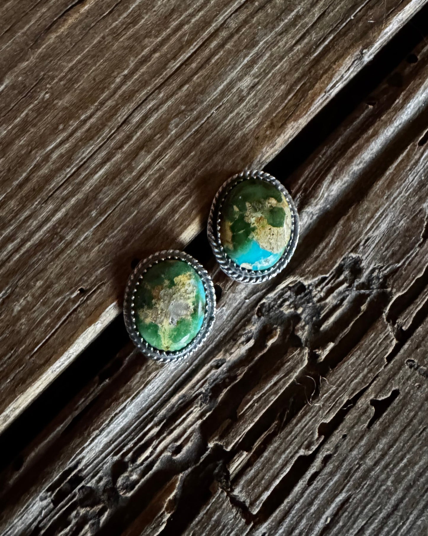 Pair of green stone earrings on a wooden surface