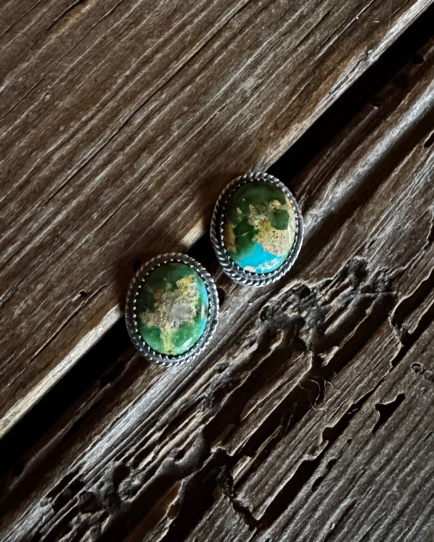 Pair of green stone earrings on a wooden surface