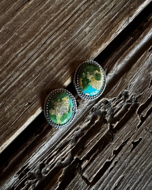 Pair of green stone earrings on a wooden surface