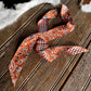Orange paisley scarf on a wooden surface with cowhide rug in the background