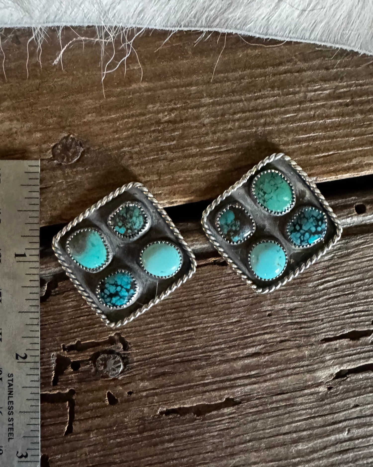 Turquoise stone brooch on a wooden surface with a ruler for scale