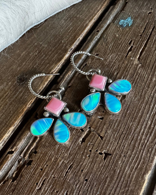 Flower-shaped earring with colorful stones on a wooden surface