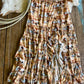 Patterned skirt on a wooden surface with cowhide rug and lasso in the background