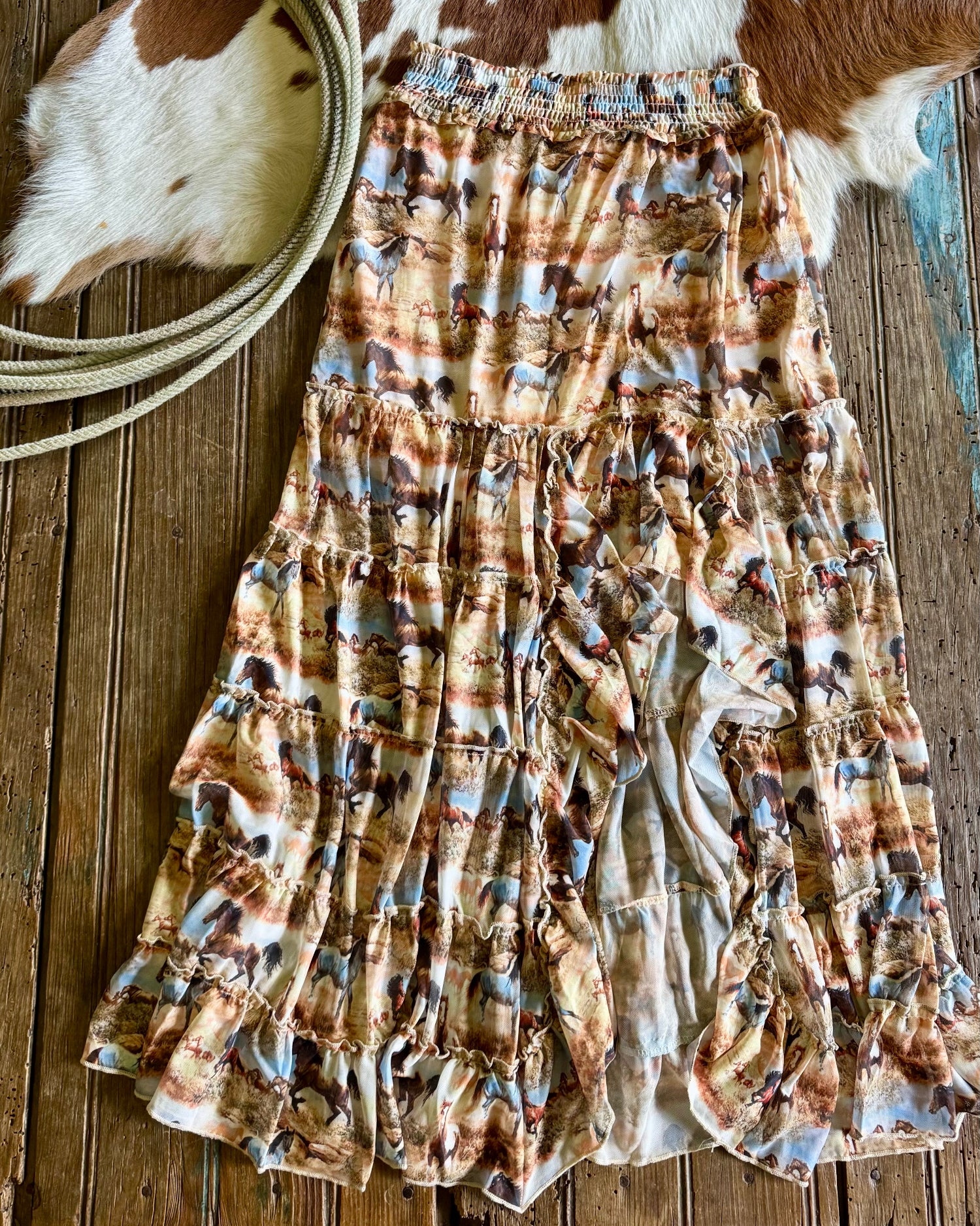 Patterned skirt on a wooden surface with cowhide rug and lasso in the background
