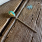 Teal pin with a decorative head on a wooden surface