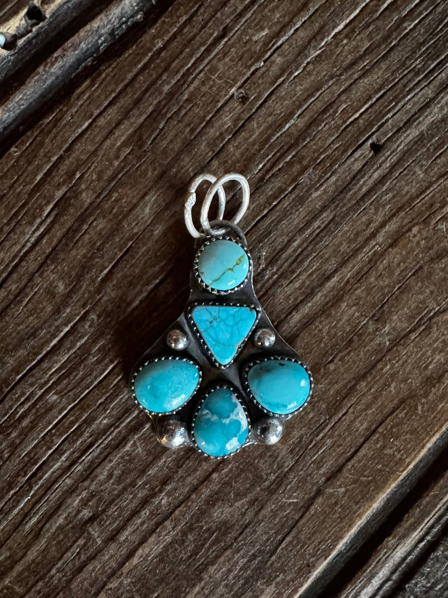 Turquoise stone and silver brooch on a wooden surface