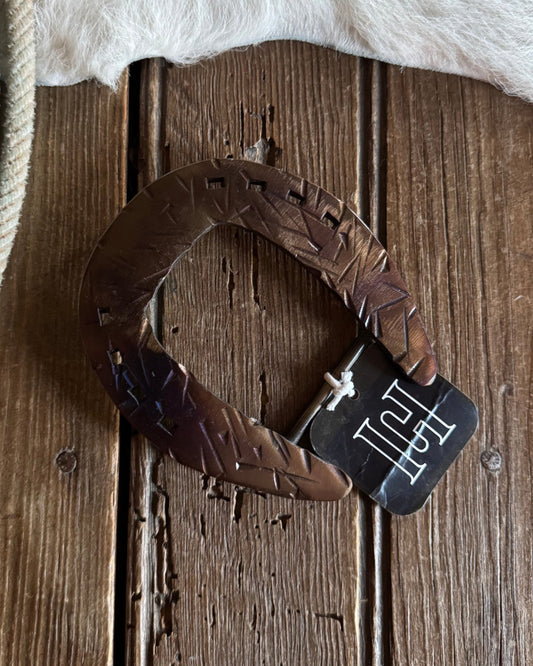 horseshoe belt buckle with a brand tag on a wooden surface next to horse hair.