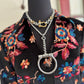 Necklace with a large silver clasp on a black mannequin wearing a floral-patterned garment.