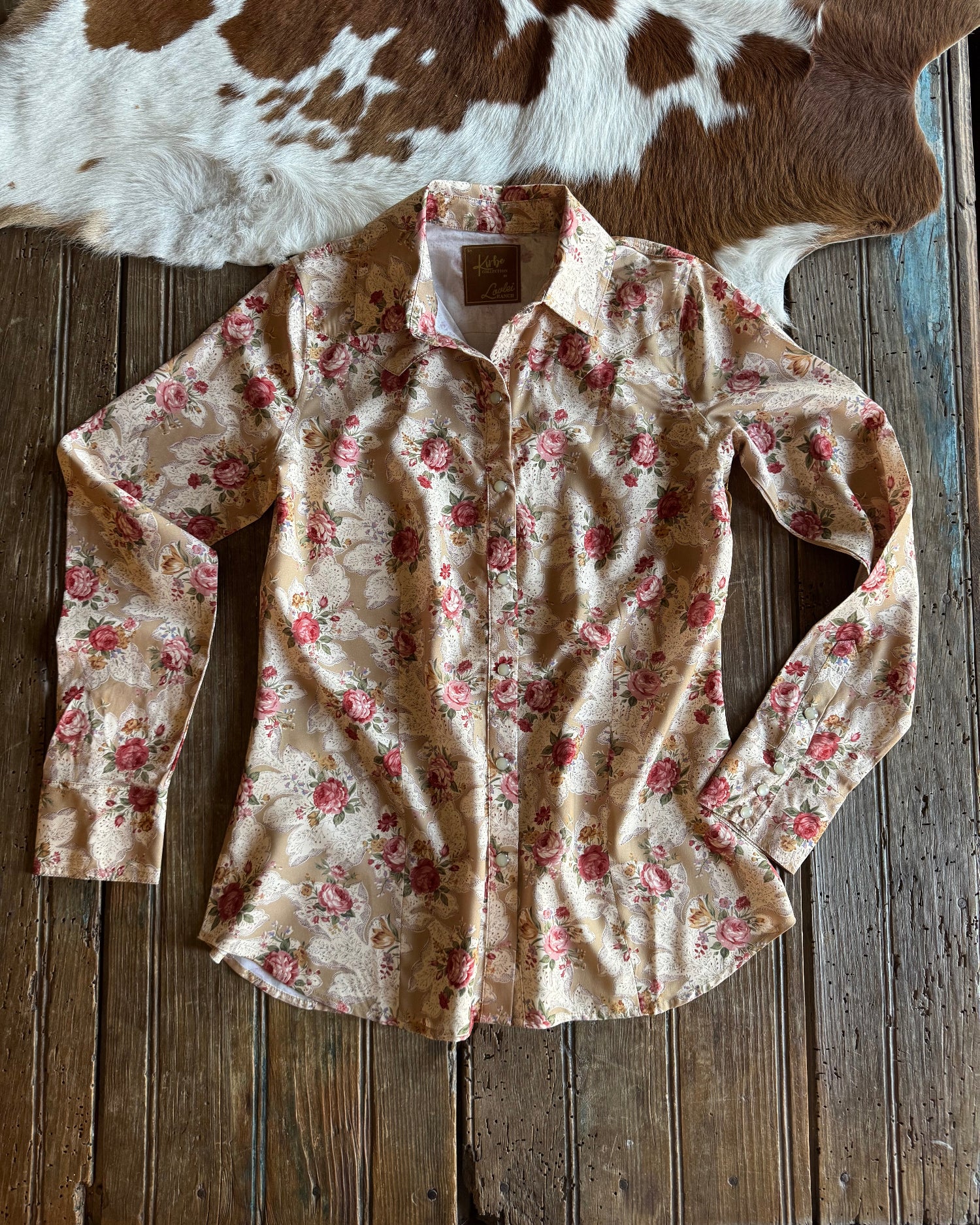 Floral-patterned shirt on a wooden surface next to a cowhide rug