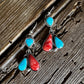 Pair of earrings with turquoise and red stones on a wooden surface