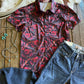 Red floral shirt and blue jeans on a wooden surface with a cowhide rug in the background.