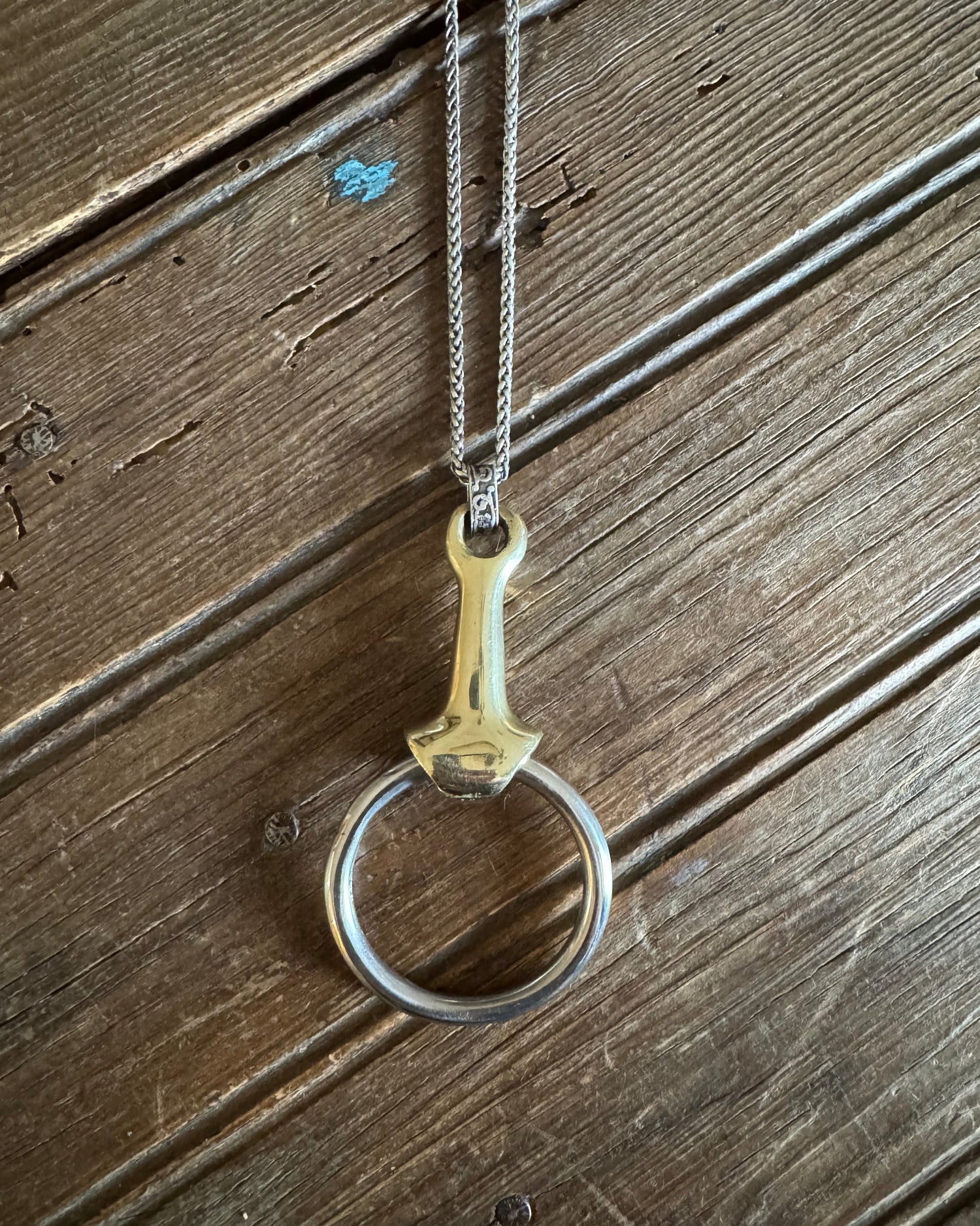 Multi metal snaffle bit necklace on rustic wood background