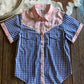 Blue checkered shirt with floral collar on a wooden surface with cowhide rug