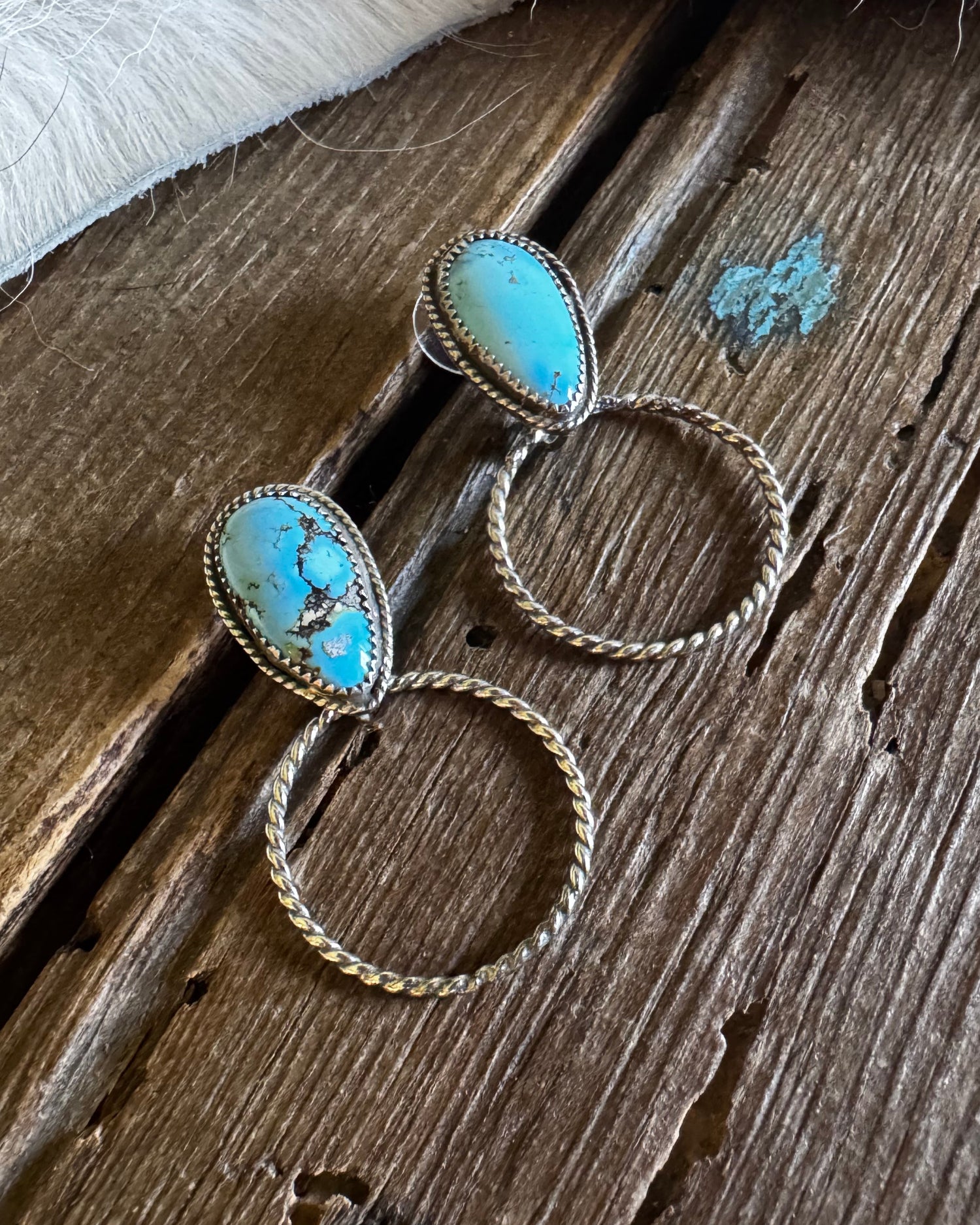 Turquoise stone earrings on a wooden surface