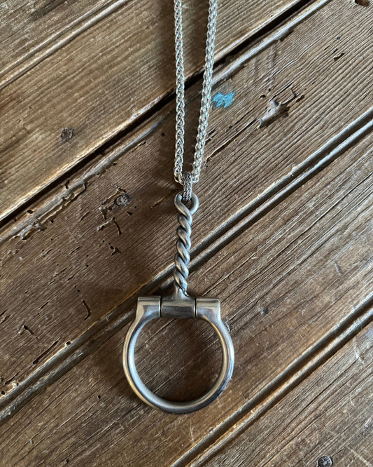 Twisted wire snaffle bit necklace on a rustic wood background