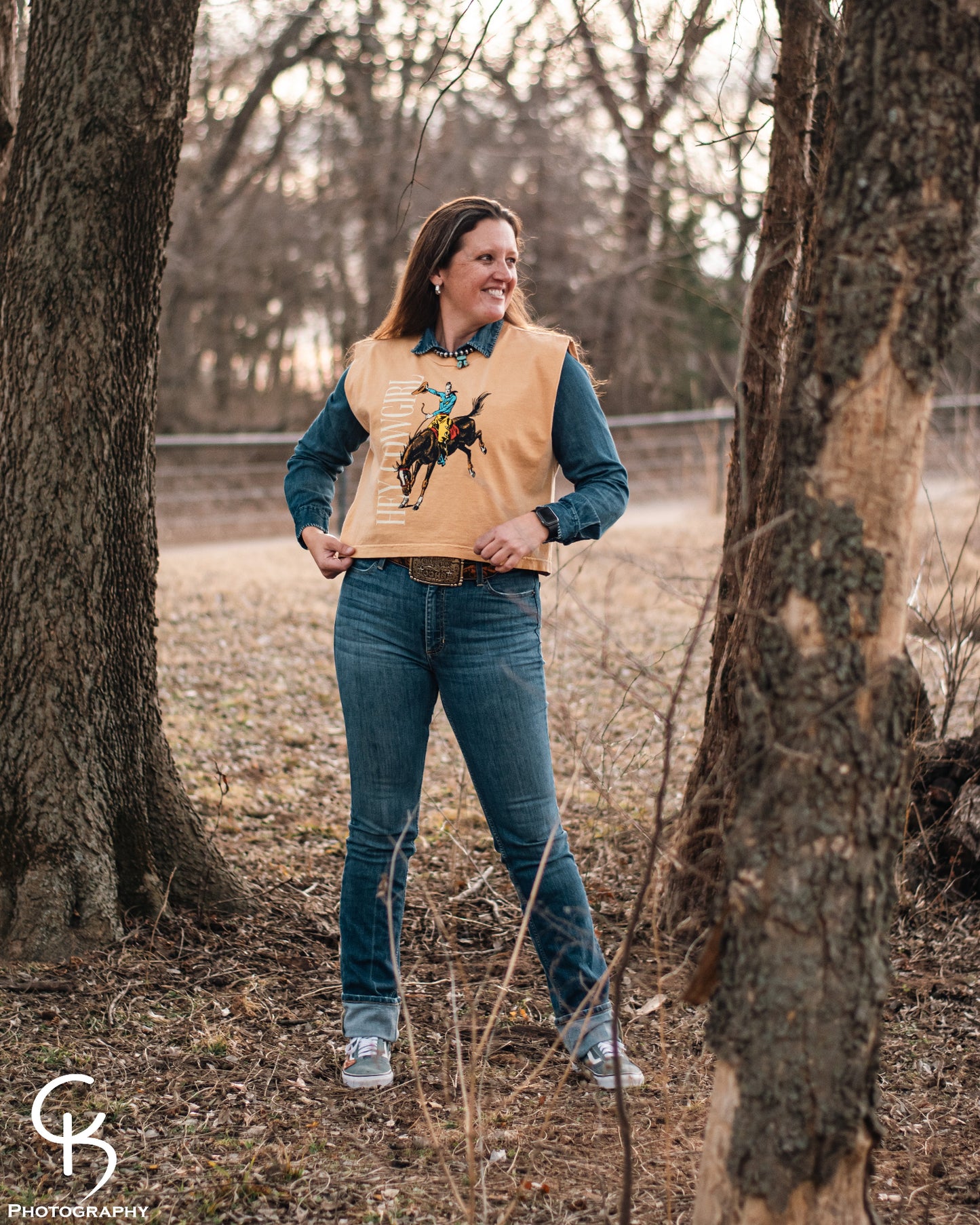 Model standing in trees, dressed in a stylish modern western outfit.