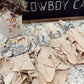 Decorative napkins with cowboy boot shapes on a countertop with a 'Cowboy' sign in the background.