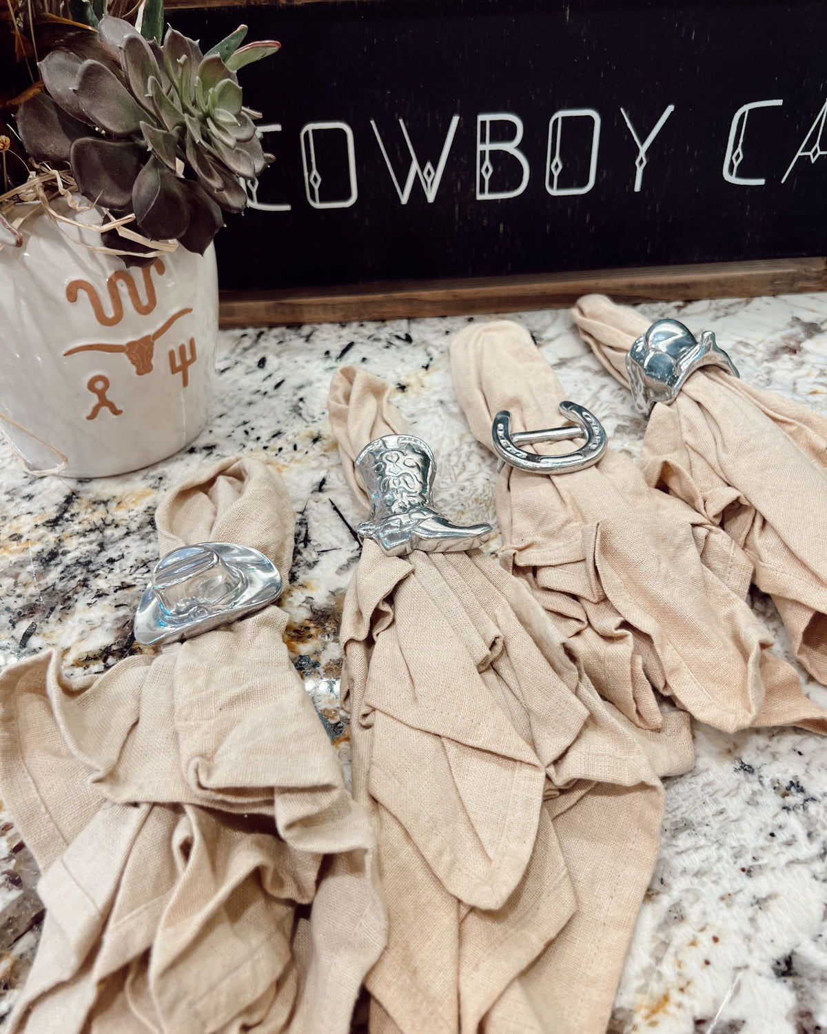Decorative napkins with cowboy boot shapes on a countertop with a 'Cowboy' sign in the background.