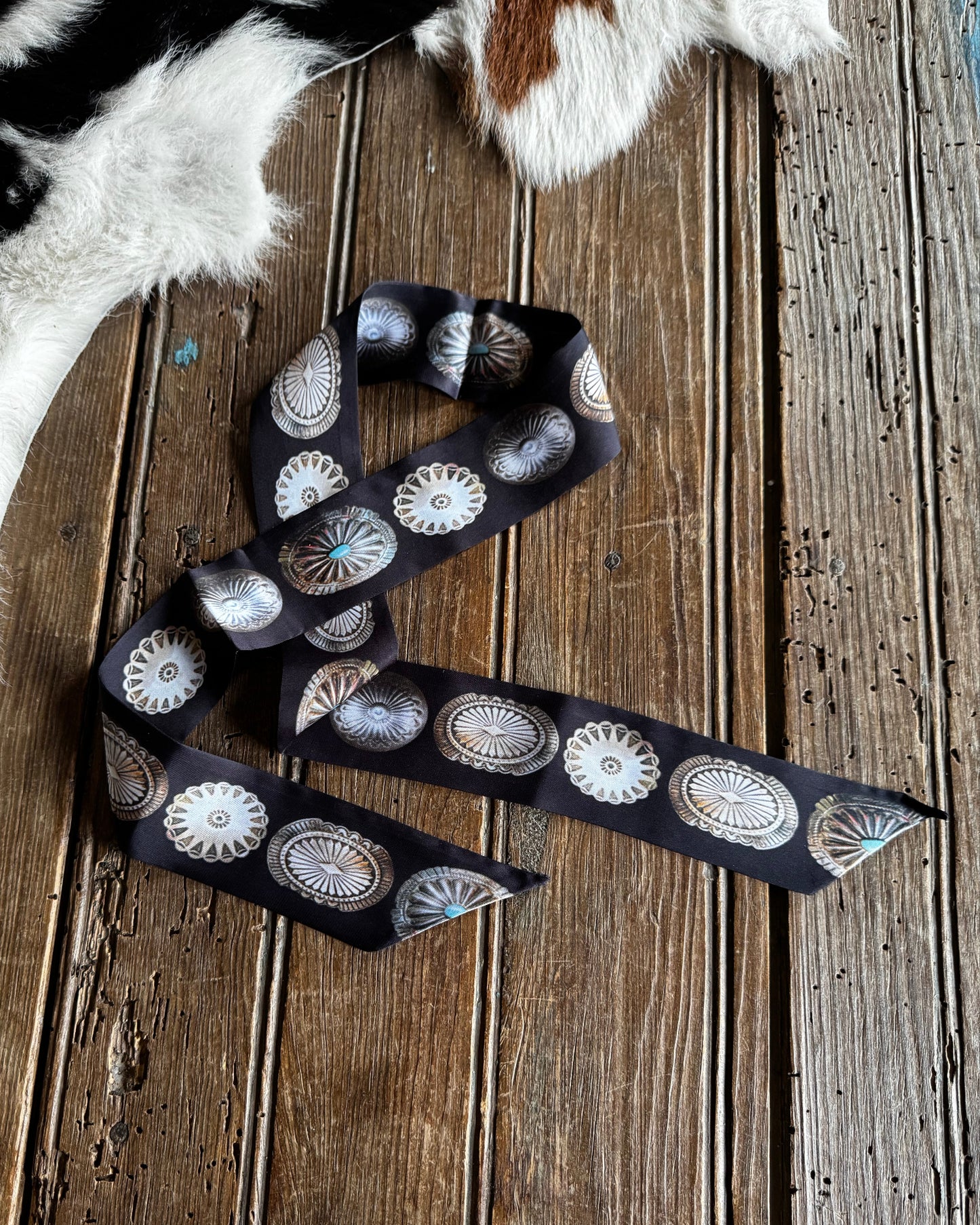 Decorative belt with concho designs on a wooden surface
