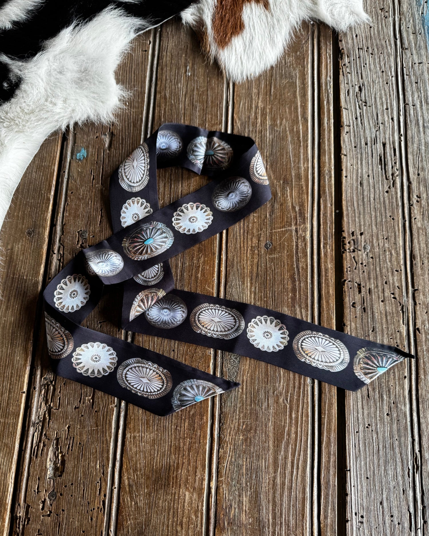 Decorative belt with concho designs on a wooden surface