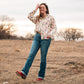 Model standing in a field, dressed in a stylish modern western outfit.