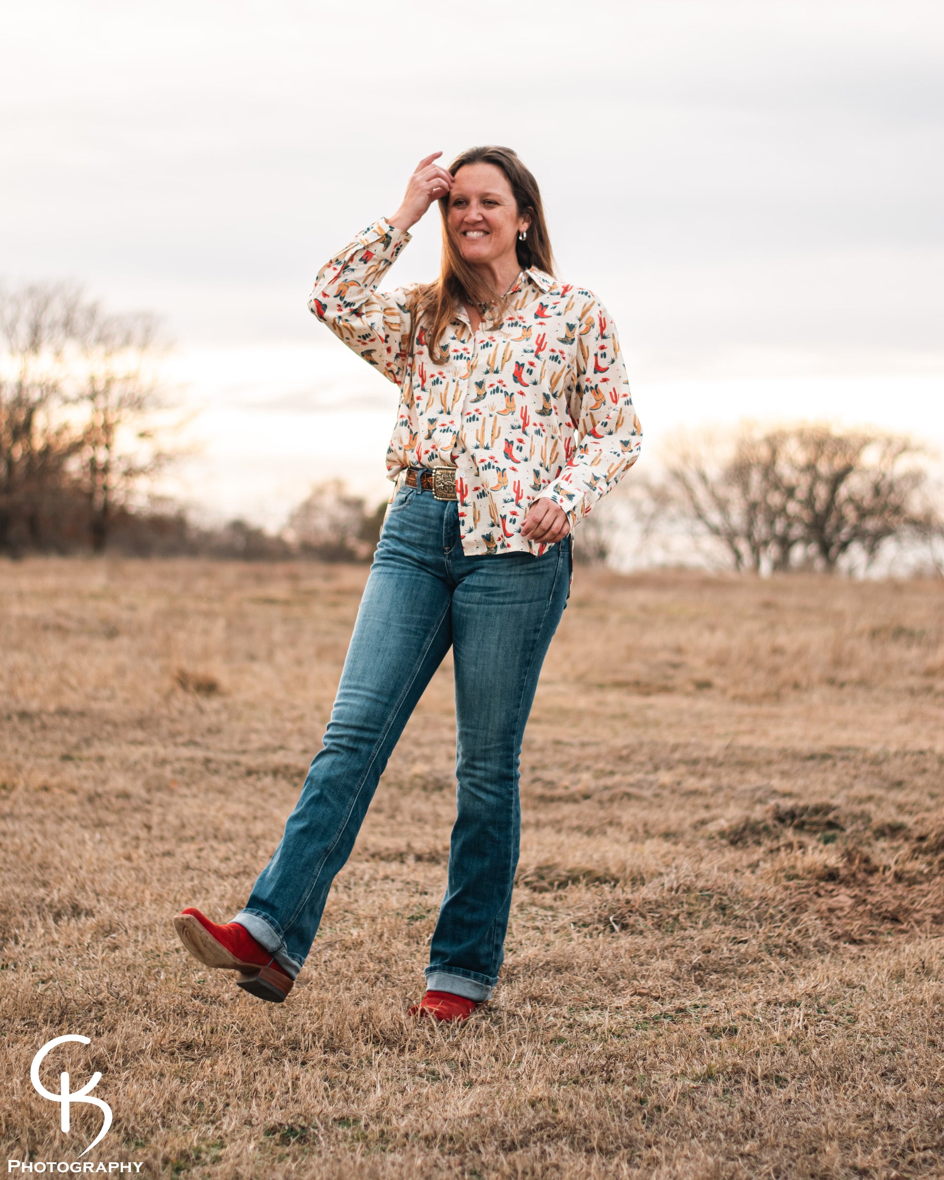 Model standing in a field, dressed in a stylish modern western outfit.