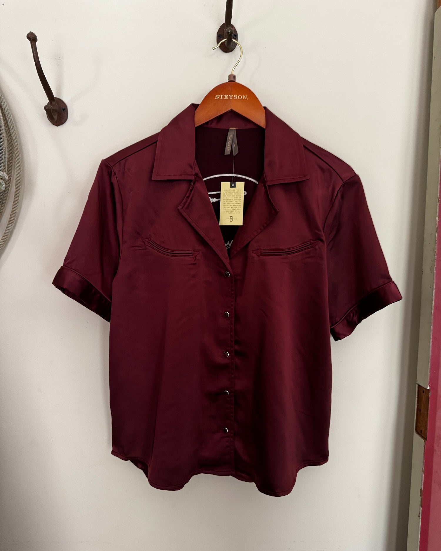 Maroon coat on a white surface with a visible brand tag.