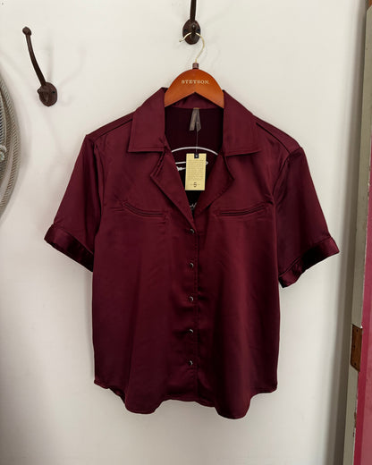 Maroon coat on a white surface with a visible brand tag.