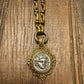 Vintage-style gold necklace with a decorative clasp on a wooden surface