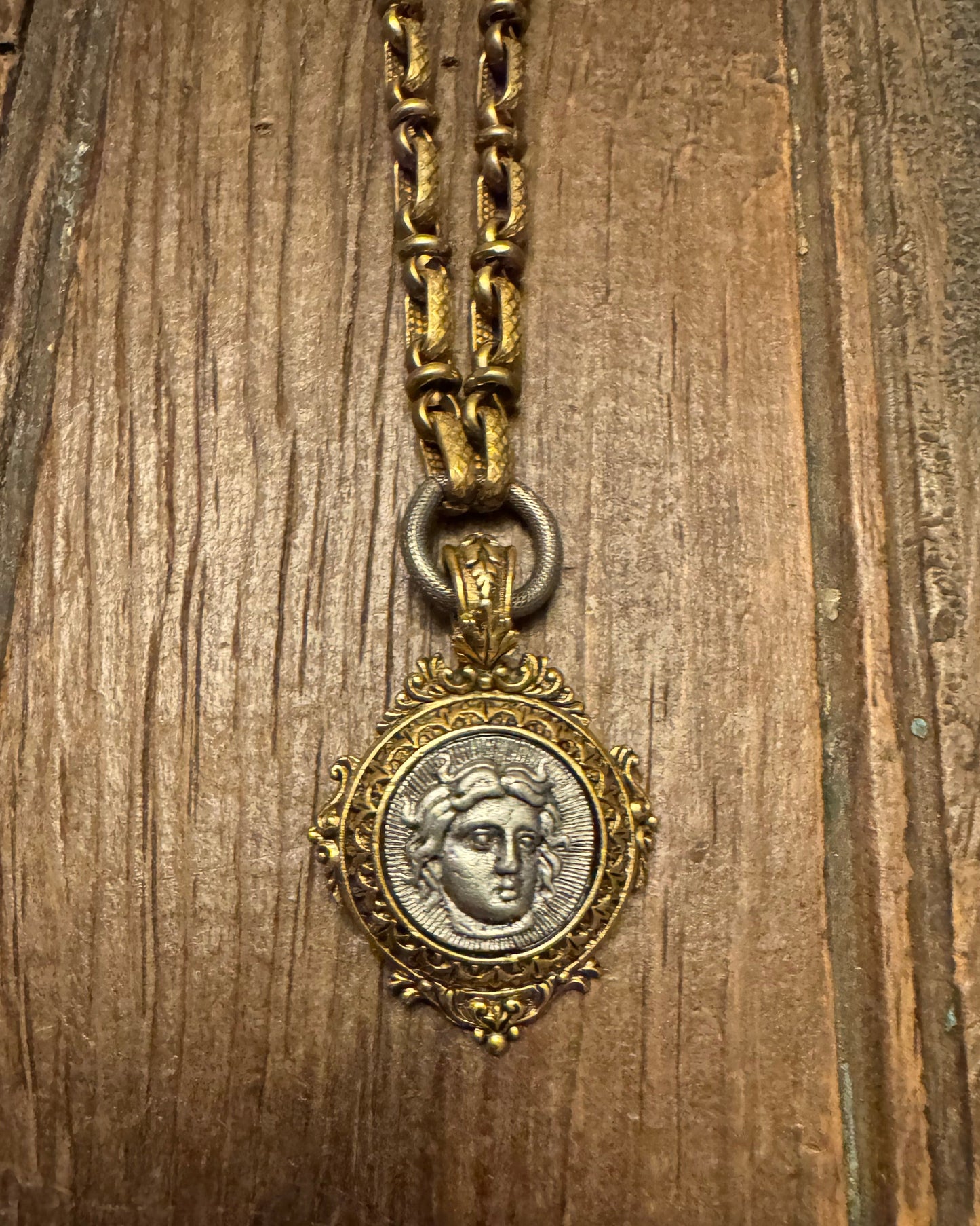 Vintage-style gold necklace with a decorative clasp on a wooden surface