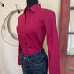 Pink shirt on a mannequin with jeans against a neutral wall.