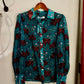 Teal shirt with red pattern on a hanger against a white wall