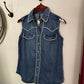 Folded denim shirt on a white surface with a fan and hook in the background
