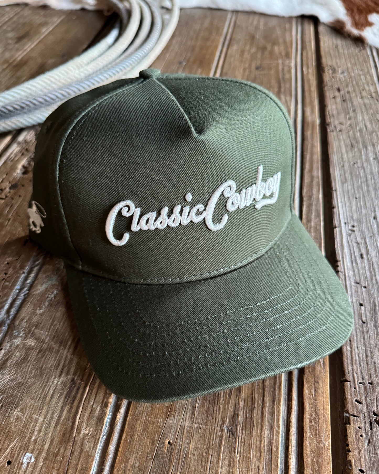 Green cap with 'Classic Cowboy' text on a wooden surface