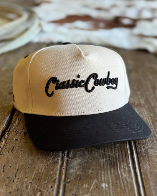 Beige and black cap with 'Classic Cowboy' text on a wooden surface