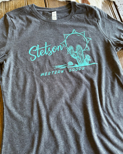 Gray t-shirt with teal 'Stetson Western Goods' logo on a wooden surface