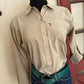 Person wearing a beige shirt and blue jeans with a belt, standing on a white floor.