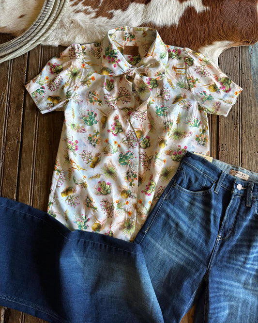 Floral shirt and blue jeans on a wooden surface with a cowhide rug.