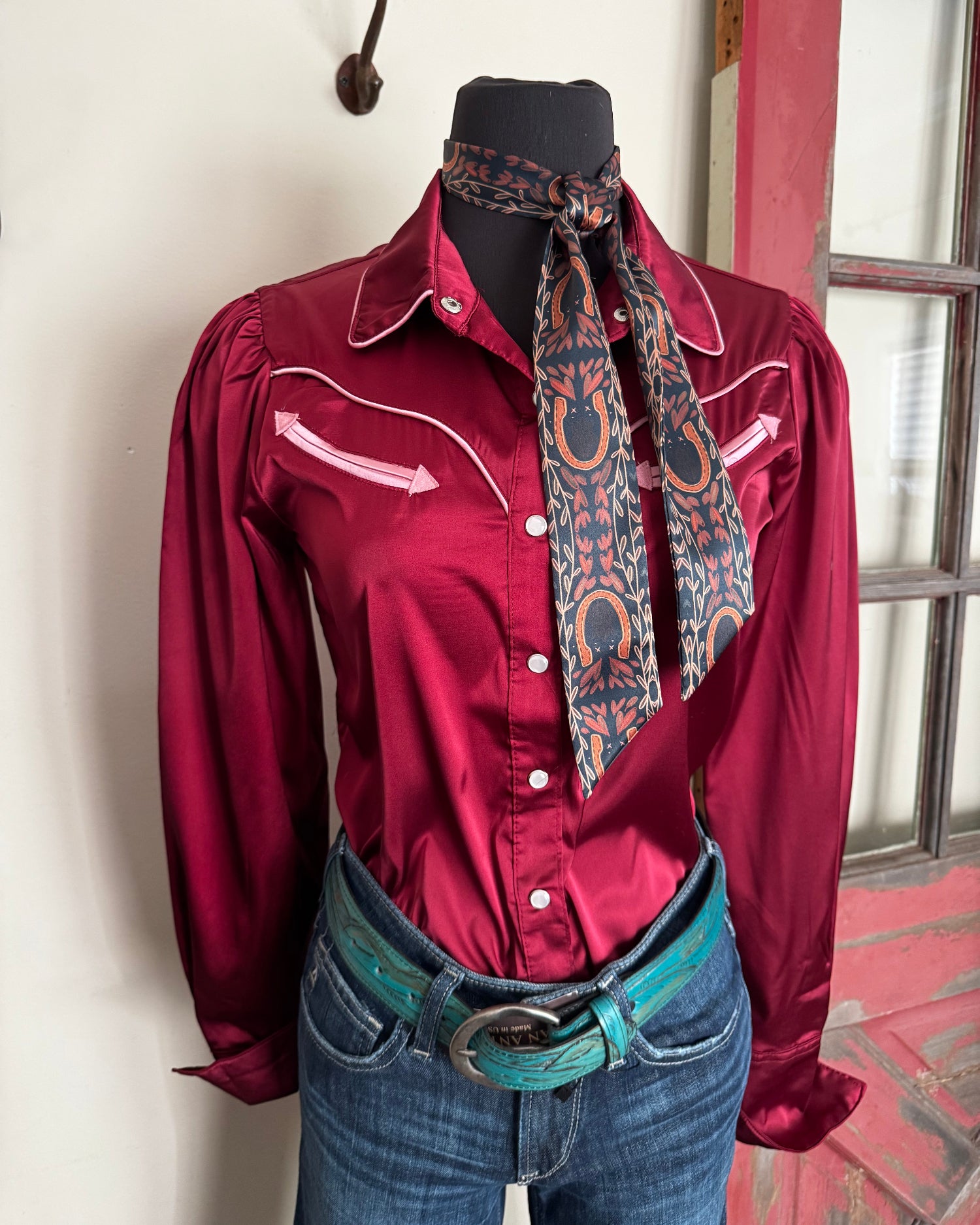 Maroon jacket with patterned tie and jeans on a white surface