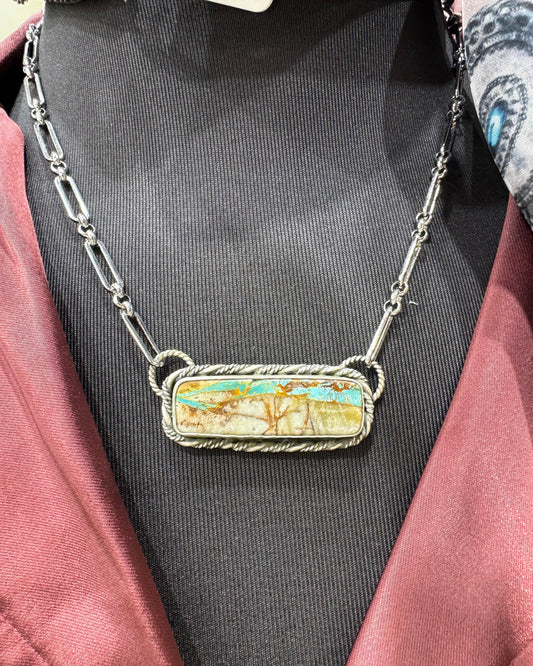 Necklace with a pendant on a person wearing a black garment.