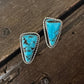 Turquoise stone earrings on a wooden surface