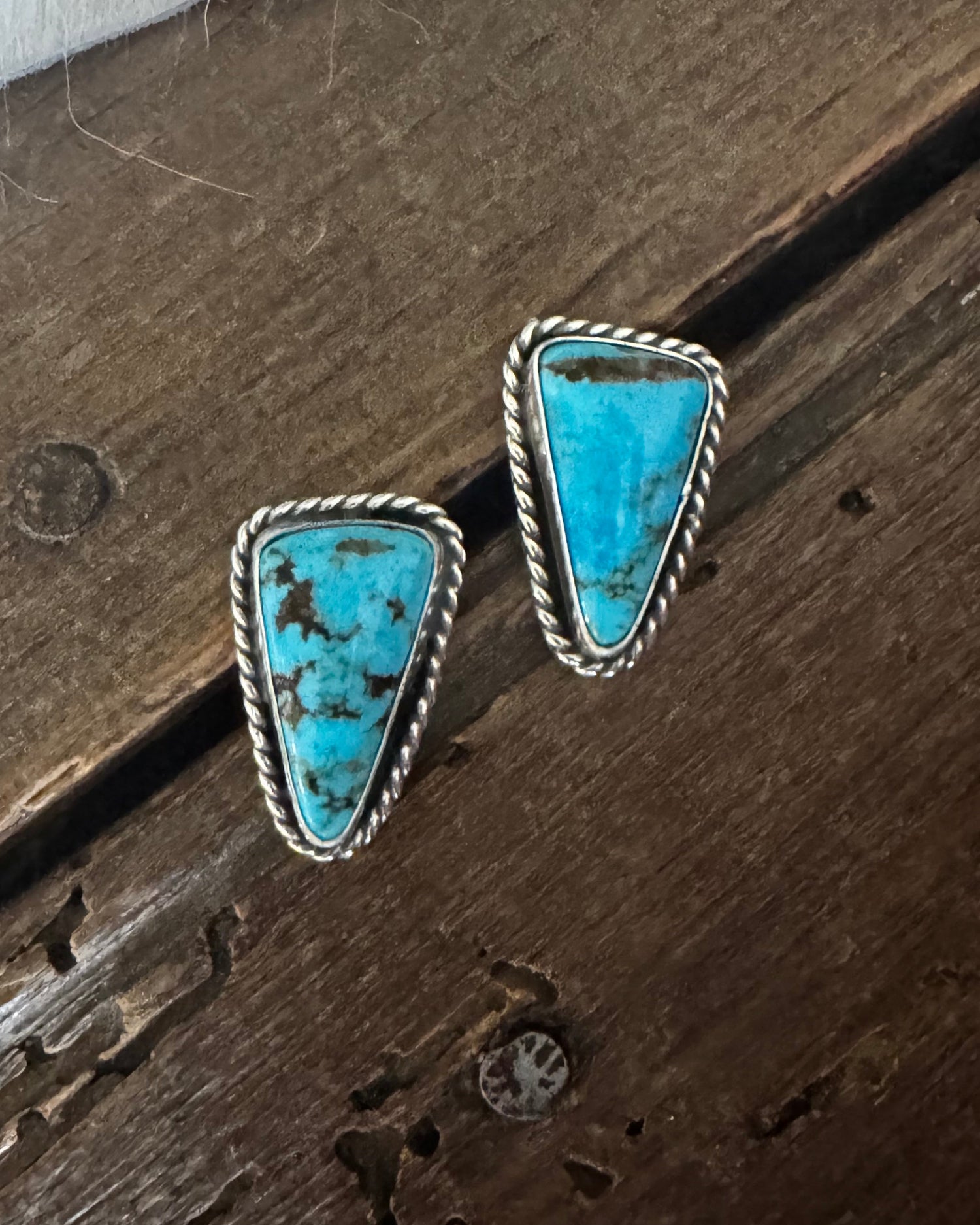 Turquoise stone earrings on a wooden surface