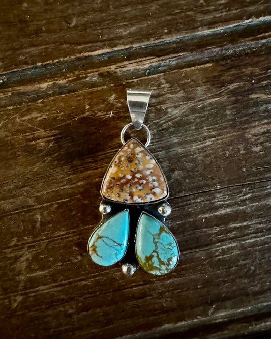 Jewelry pendant with turquoise and brown stones on a wooden surface