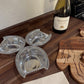Three metal wine coasters on a wooden surface with a bottle of Meiji wine in the background.