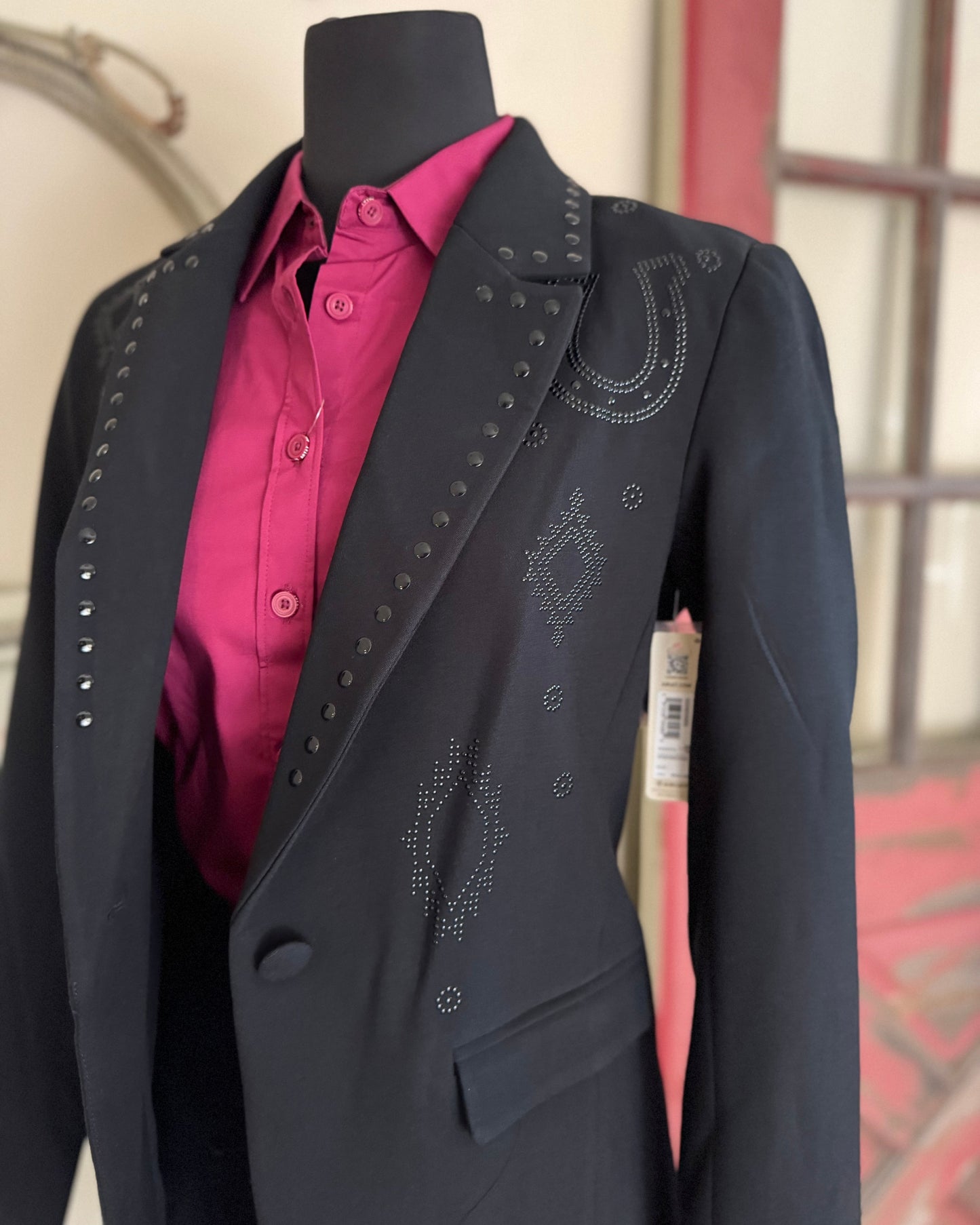 Black blazer with pink shirt on a mannequin against a neutral background