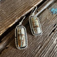 Pair of earrings with stone and silver setting on a wooden surface