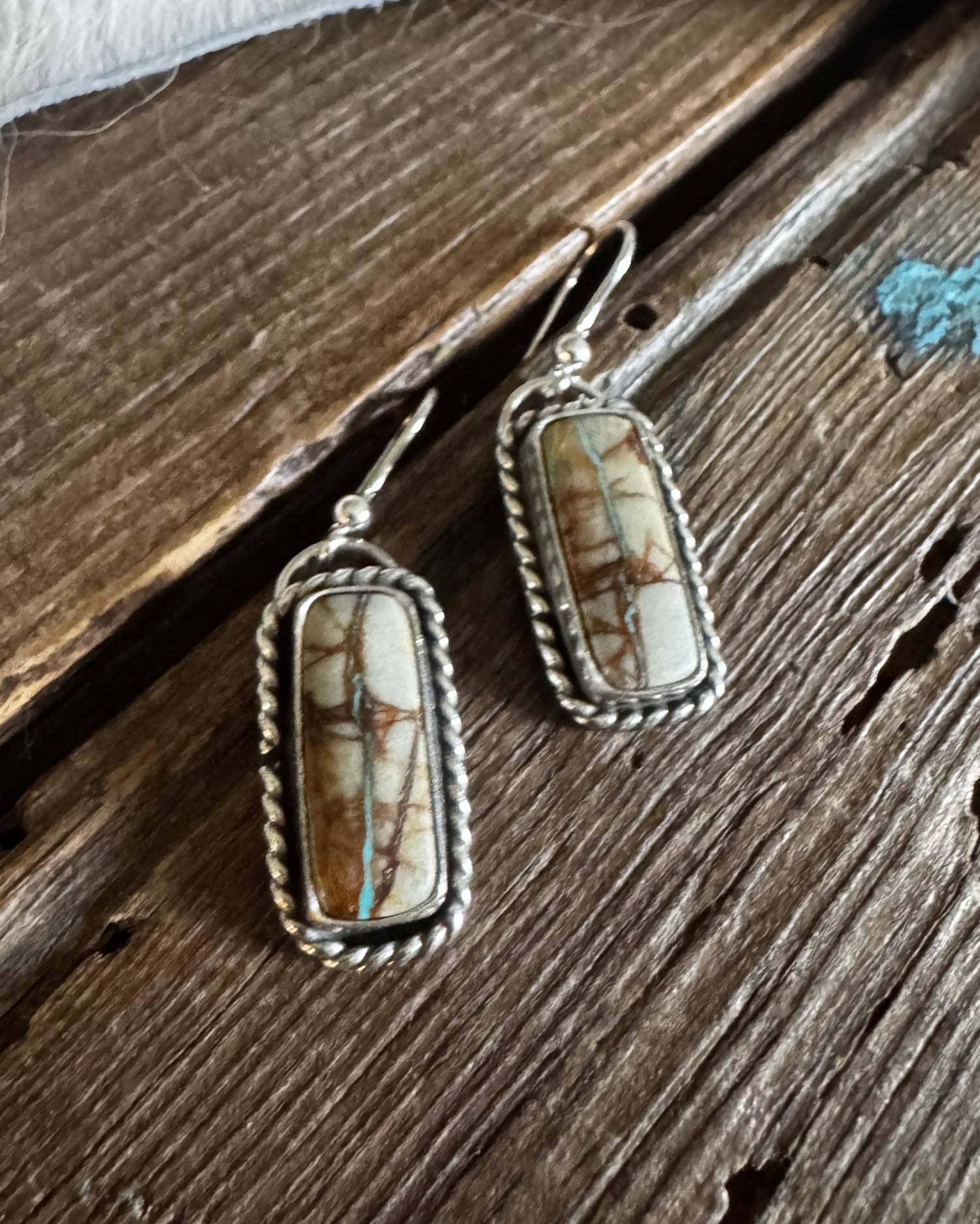 Pair of earrings with stone and silver setting on a wooden surface