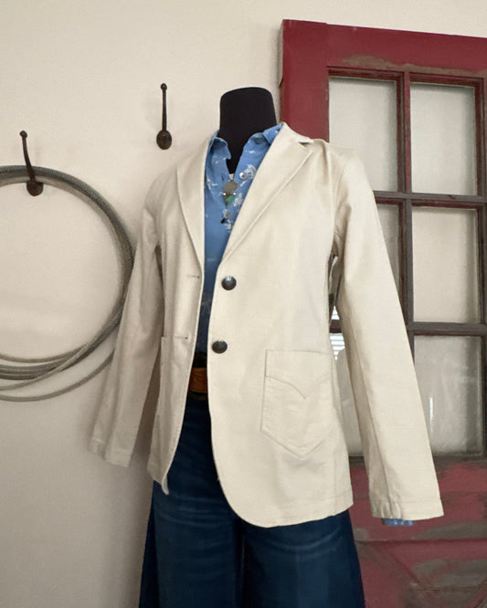 Cream jacket with black buttons on a hanger against a neutral background