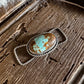Turquoise stone pendant on a wooden surface with fur in the background