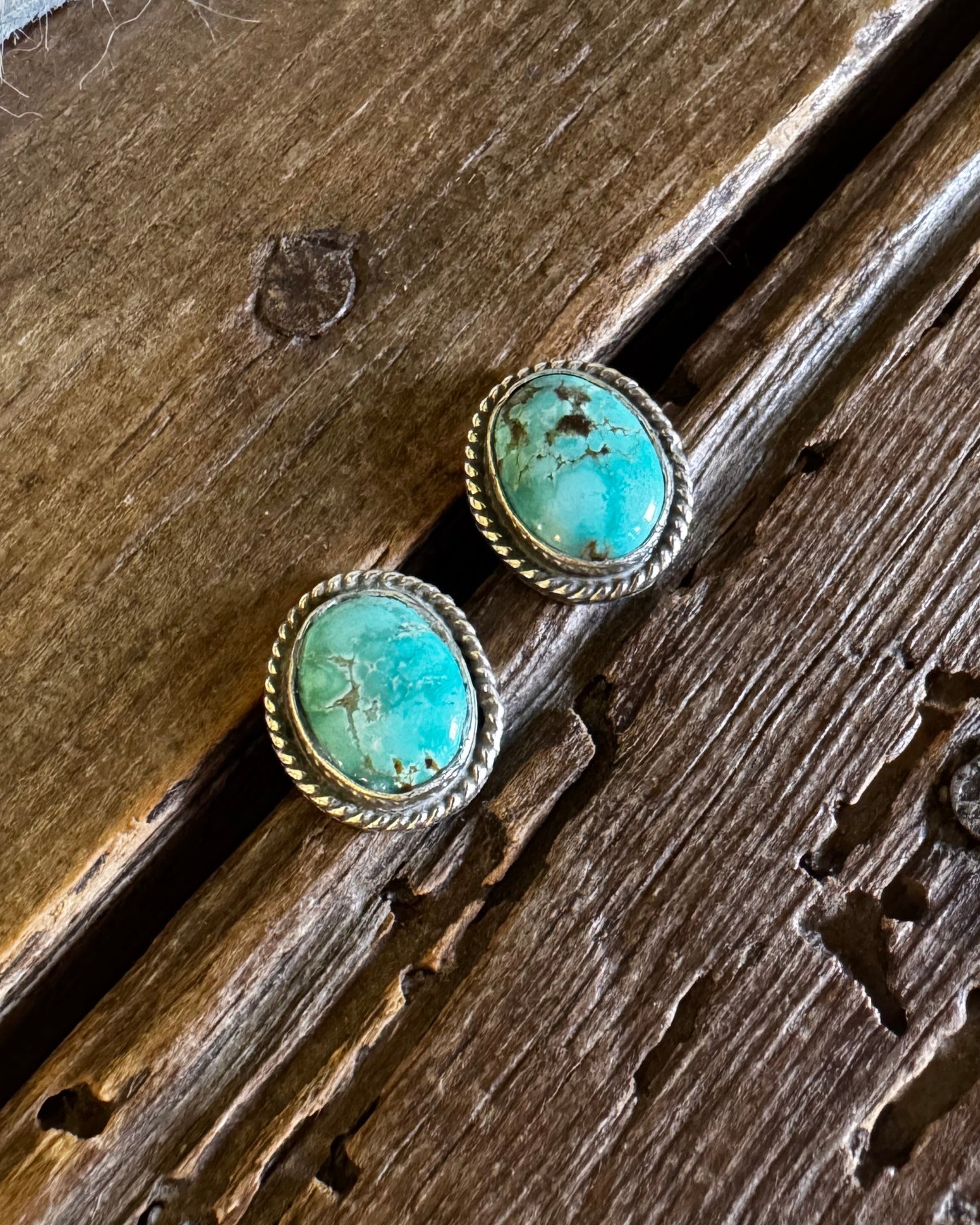 Turquoise stud earrings on a wooden surface